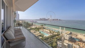 Een balkon met uitzicht op een strand, een reuzenrad en een stadsbeeld.