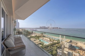 Un balcon avec vue sur une plage, une grande roue et le paysage urbain.