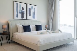 A modern bedroom with a large bed, two bedside tables, and a view of the city.