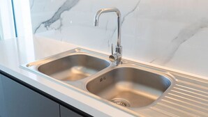 A modern kitchen with a double stainless steel sink, a sleek faucet, and a marble backsplash. - Beautiful 2 Bedroom Sea Views at La Vie JBR (Dubai)
