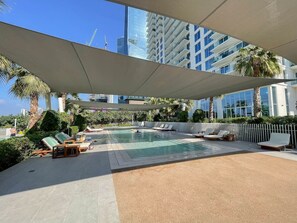 A rooftop pool area with lounge chairs and a view of high-rise buildings.