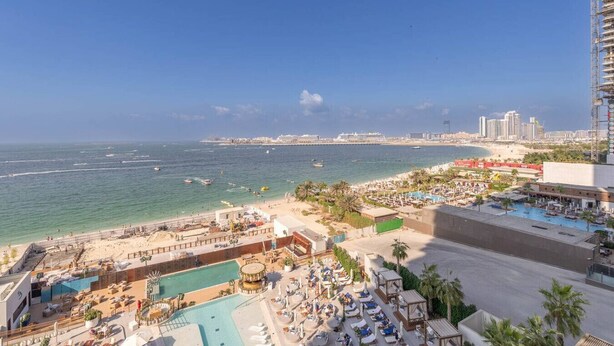 A hotel with a pool area, beach access, and a view of the ocean and city skyline. - Beautiful 2 Bedroom Sea Views at La Vie JBR (Dubai)
