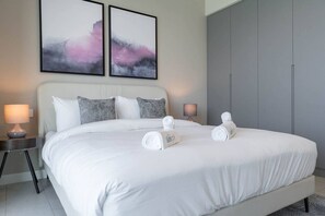 A modern hotel room with a large bed, two bedside tables with lamps, and abstract artwork on the wall.