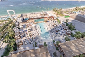 A resort with a large pool, sun loungers, and a beach area.
