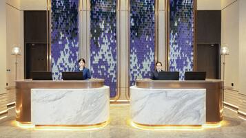 Zona de recepción con mostradores de mármol y una pared decorada con mosaicos.