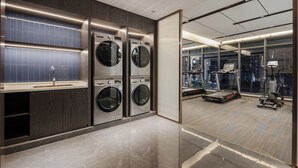 Une buanderie moderne équipée de deux machines à laver, d’un évier et offrant une vue sur la ville grâce à de grandes fenêtres.