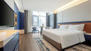 Une chambre d’hôtel moderne équipée d’un grand lit, d’une télévision, d’un bureau et d’une chaise.