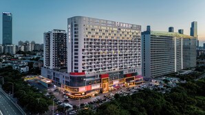 Un hôtel à plusieurs étages, doté d’un design moderne, comprenant un grand parking et une entrée imposante.