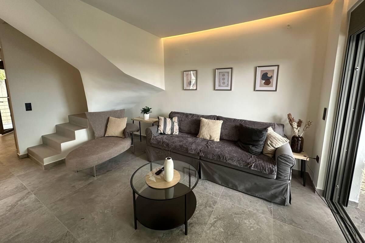 A modern living room with a sofa, a coffee table, and a staircase.