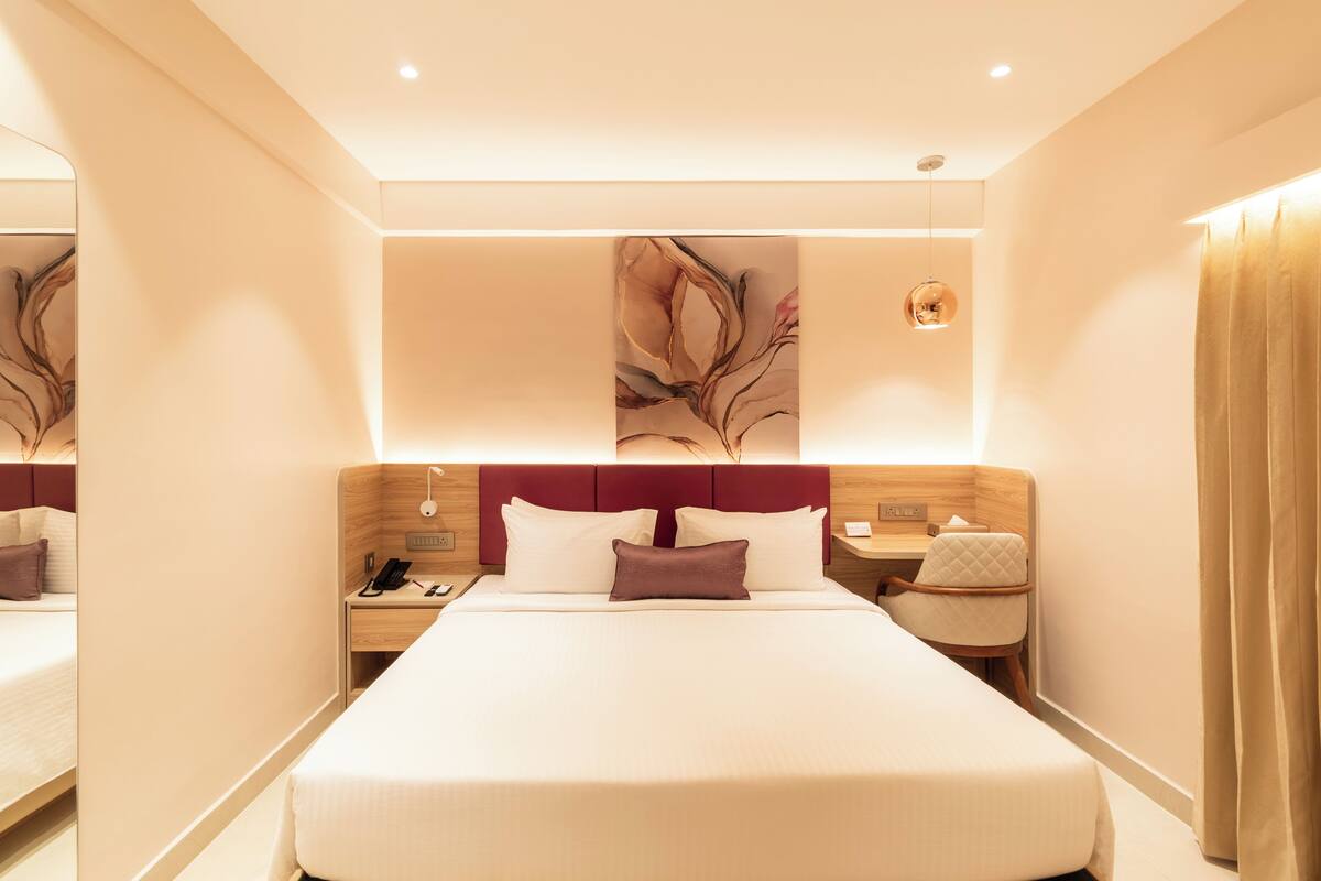 Quarto de hotel moderno com uma cama grande, uma escrivaninha e uma mesa de cabeceira.