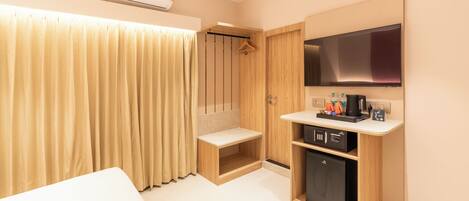 A hotel room with a bed, a TV, a minibar, and a shower area.