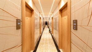 A modern hotel corridor with marble flooring, wooden paneling, and illuminated signs indicating room numbers 309 and 310.