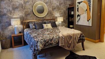 A bedroom with a bed, bedside lamps, a round mirror, a bookshelf, and a framed artwork on the wall.