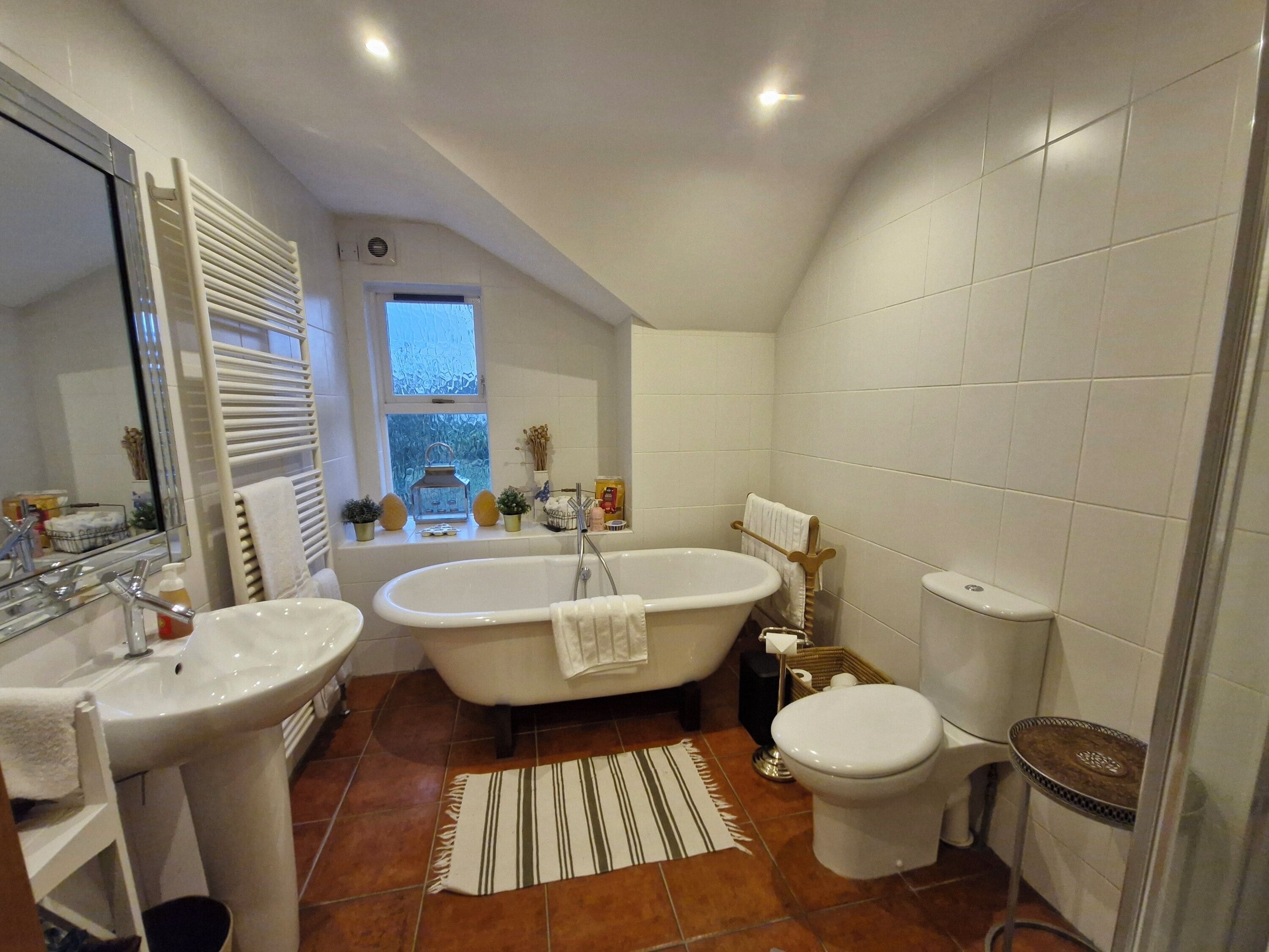 Un baño con bañera, dos lavamanos, inodoro y ventana.