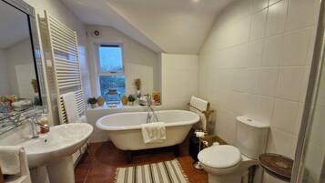 Un baño con bañera, dos lavamanos, inodoro y ventana.