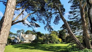 A residential property with a well-maintained lawn, a large tree, and a house with a sloped roof. - Drumee Lodge (Castlewellan)
