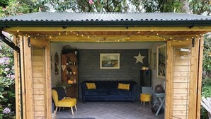 A cozy wooden cabin with a herringbone floor, a dark blue sofa, a yellow armchair, and a small table. - Drumee Lodge (Castlewellan)