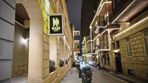 A narrow street lined with buildings, one of which has a sign for the Hazz Hotel.