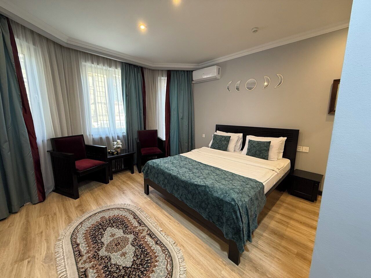 A hotel room with a bed, a desk, a chair, and a rug.