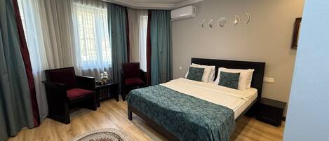 A hotel room with a bed, a desk, a chair, and a rug.
