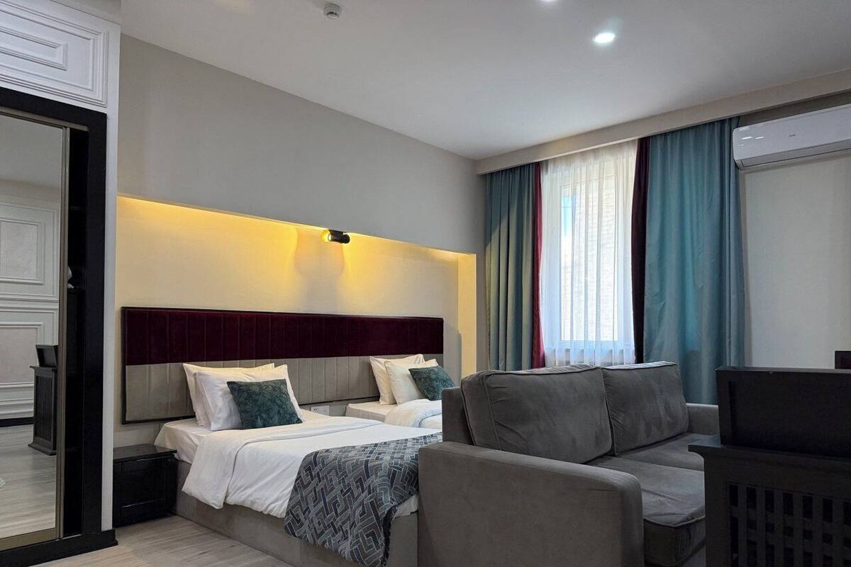 A modern hotel room with a bed, a sofa, and a TV.