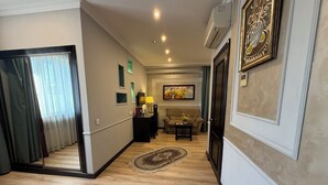 A hallway with a wooden floor, a sofa, a coffee table, and a painting on the wall.