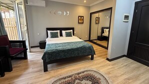 A modern bedroom with a bed, a chair, a mirror, and a door.