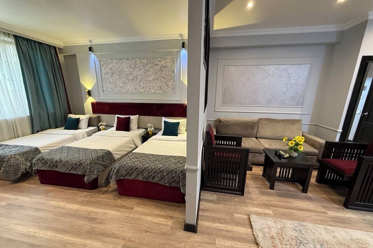 A hotel room with two beds, a sofa, a coffee table, and a small table with flowers.