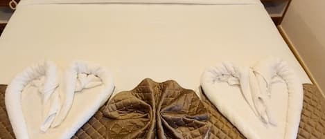 Una cama bien tendida con edredón blanco y dos almohadas acolchadas marrones.