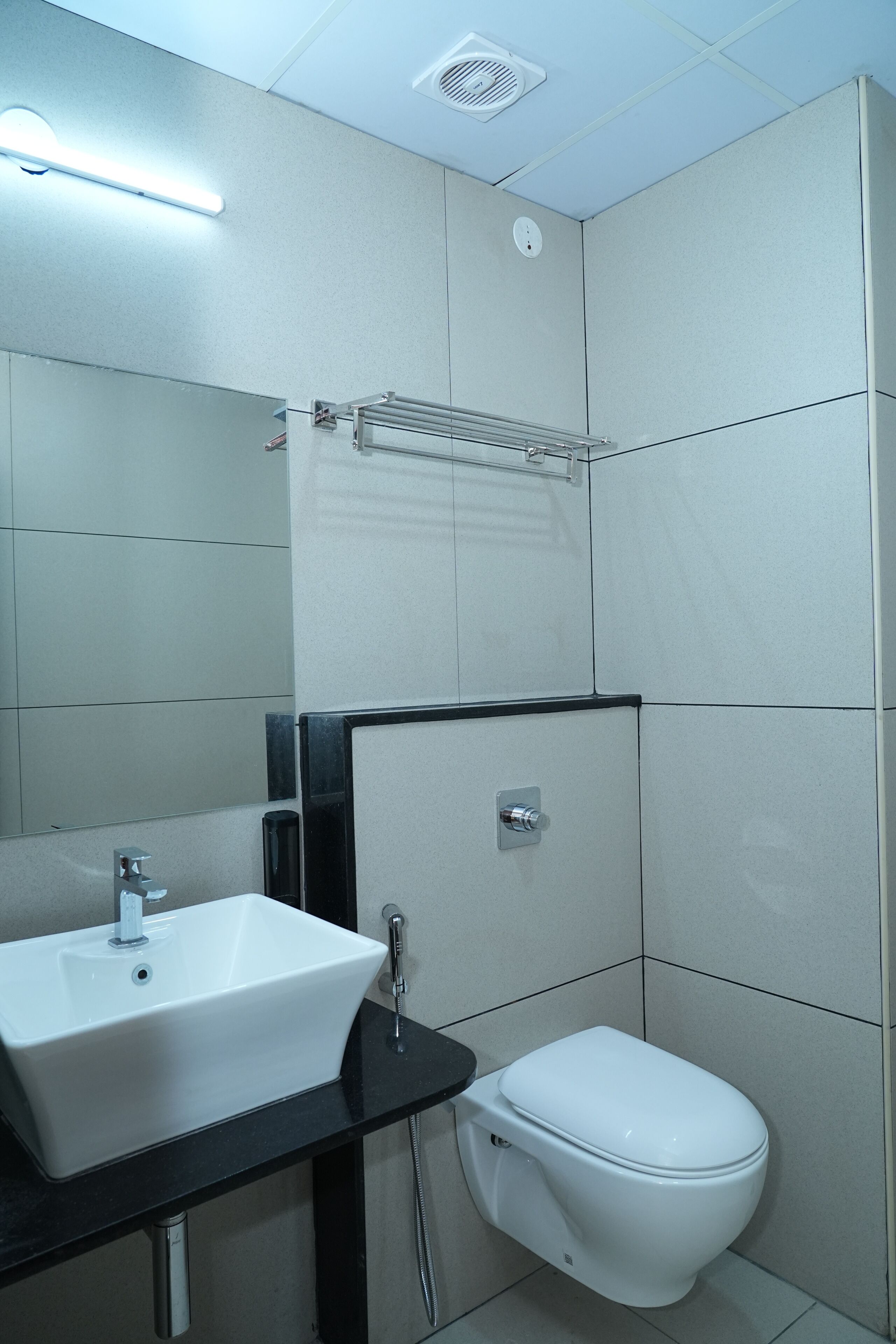 Une salle de bain avec un lavabo blanc, un plan de toilette noir et des toilettes blanches.