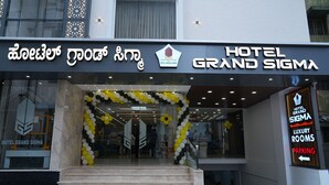 The entrance of Hotel Grand Sigma with a black and white balloon archway and a sign indicating luxury rooms and parking. - Hotel Grand Sigma (Bengaluru)