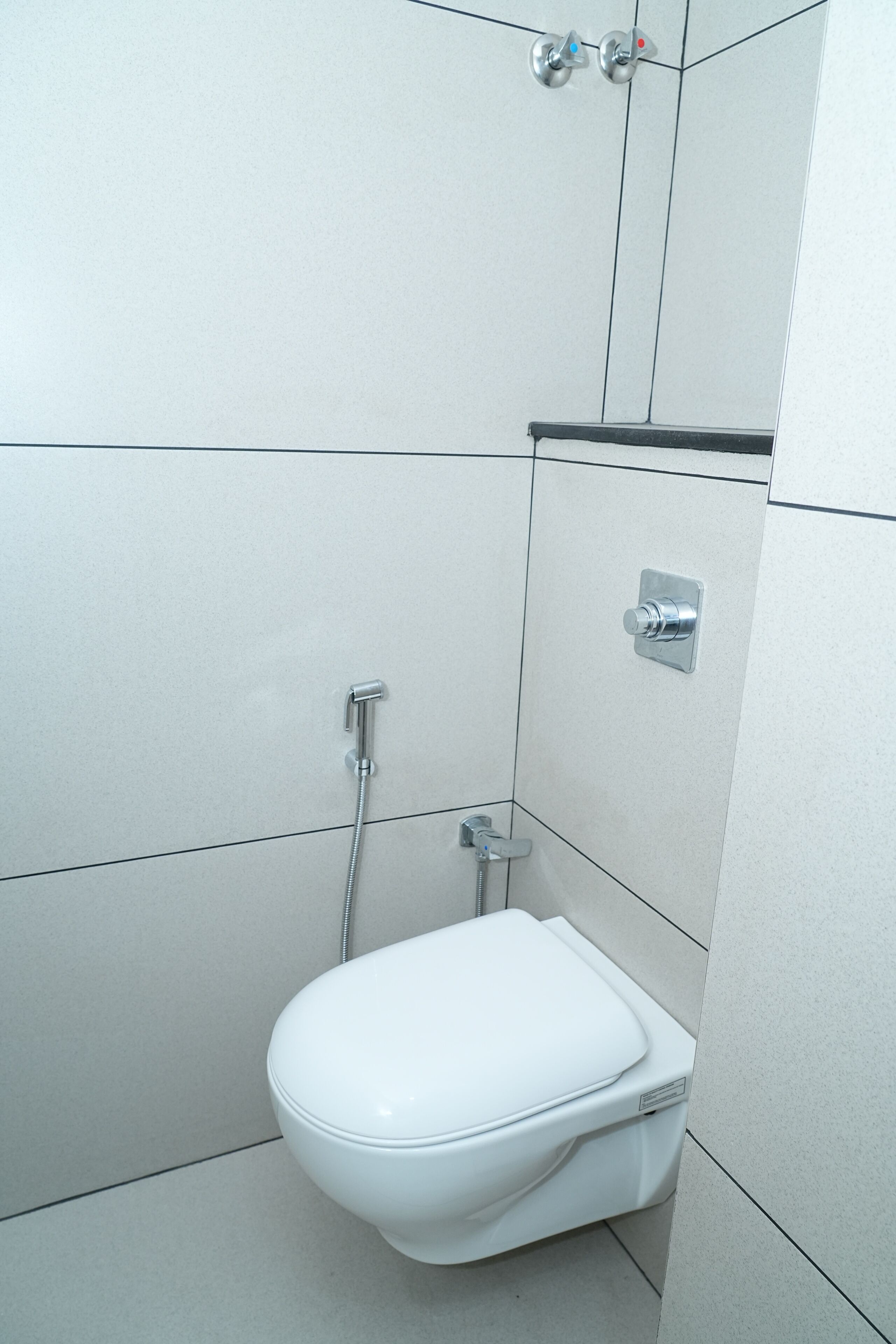 A small, modern bathroom with a white toilet, a shower, and a sink.