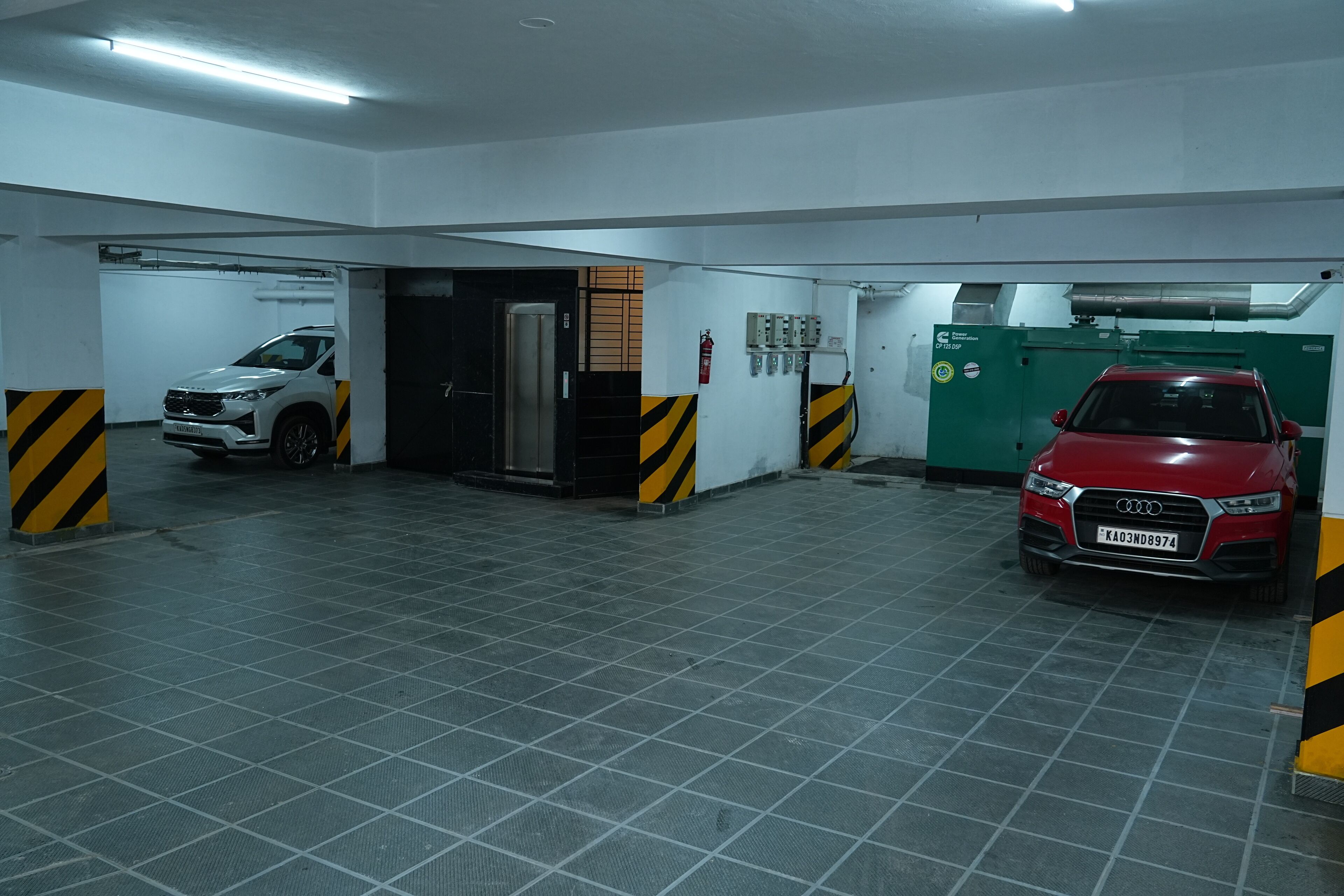 Un garaje de estacionamiento con dos coches aparcados, un extintor y una máquina verde.