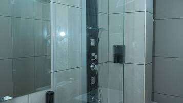 Un baño moderno con ducha envuelta en vidrio, un lavabo blanco y un inodoro.