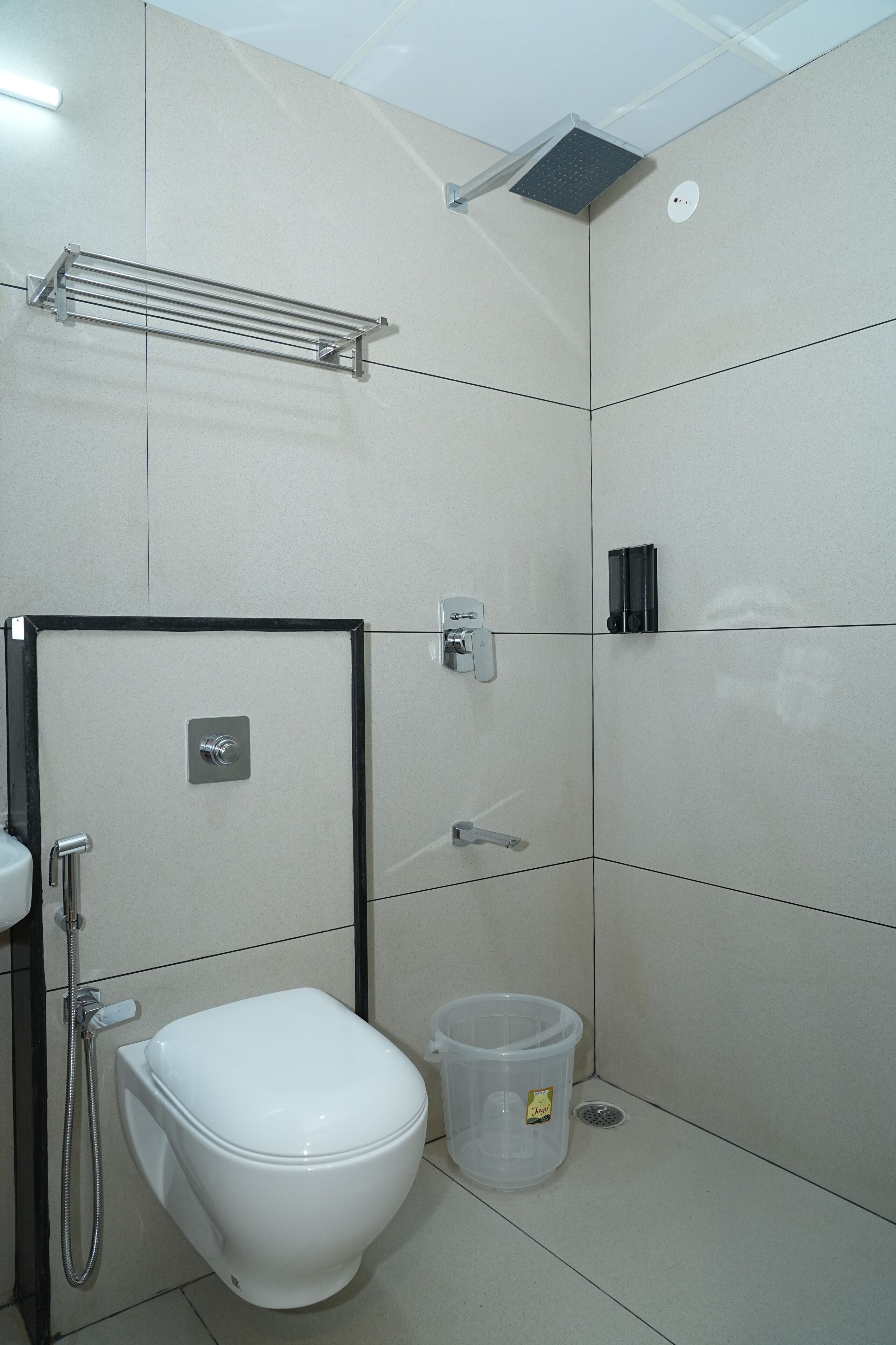 A modern bathroom with a toilet, shower, and a clear plastic waste bin.