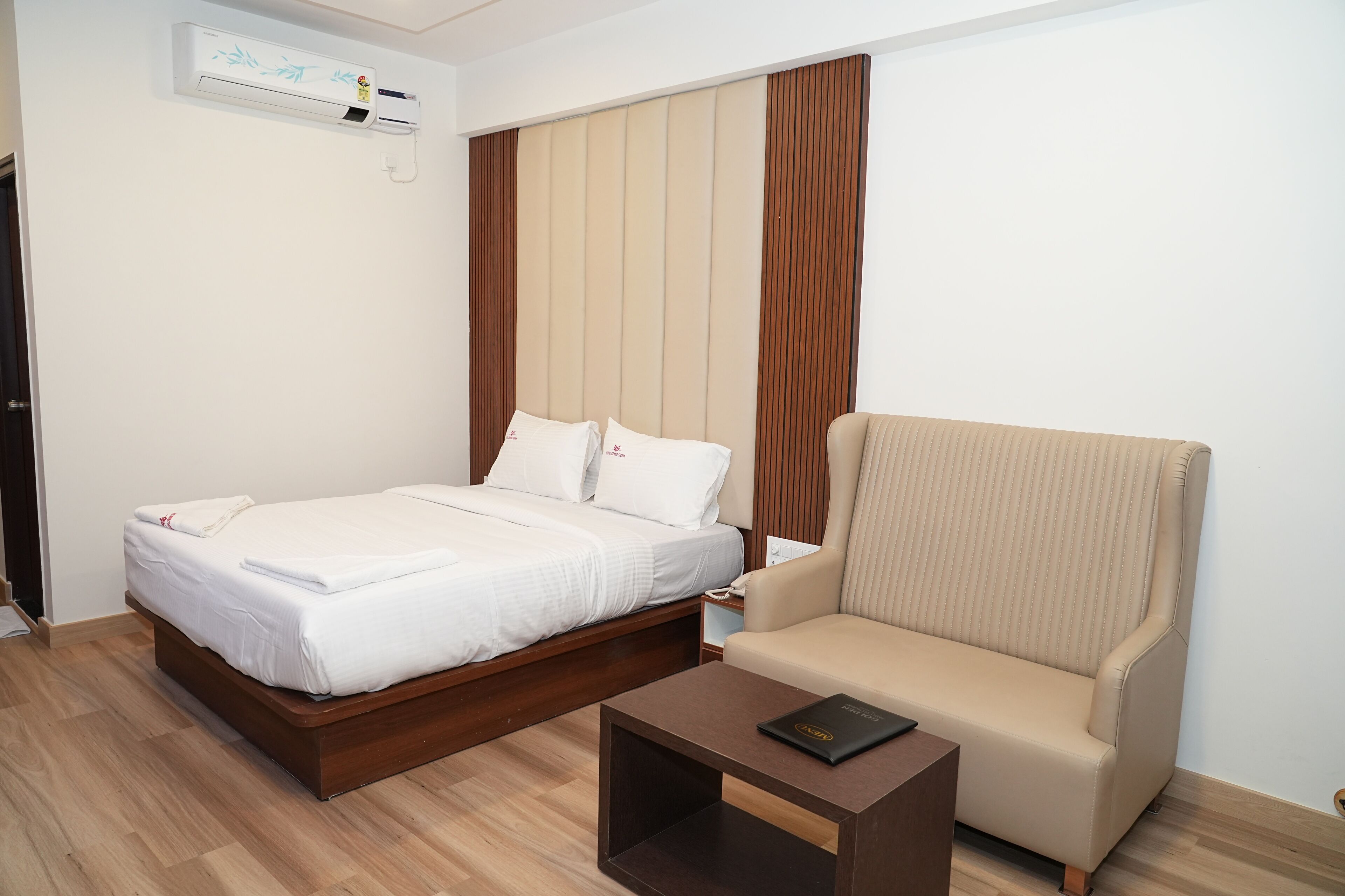 Une chambre d’hôtel équipée d’un lit, d’un canapé, d’une table de chevet et d’un appareil de climatisation.