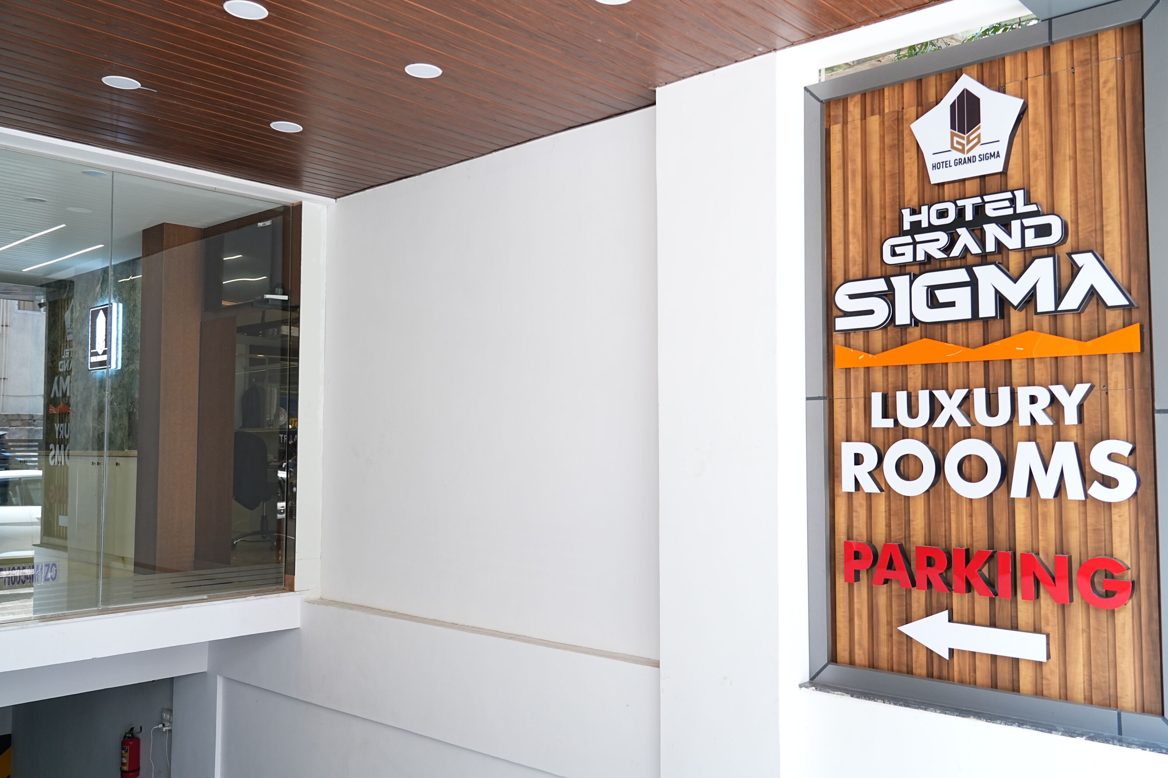 A sign for Hotel Grand Sigma Luxury Rooms with a direction to parking.