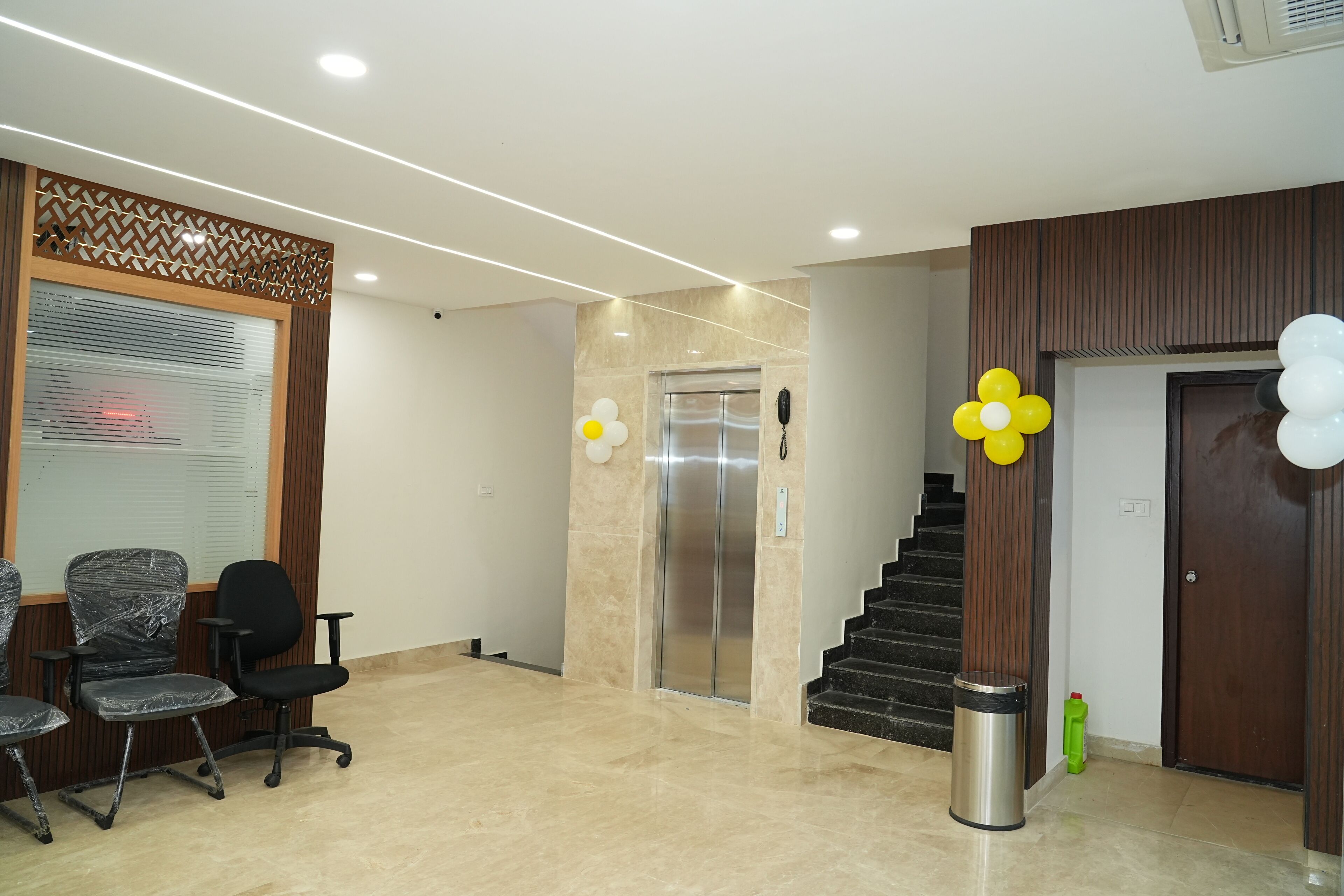 A reception area with a reception desk, office chairs, an elevator, and a staircase.