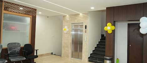 A reception area with a reception desk, office chairs, an elevator, and a staircase.