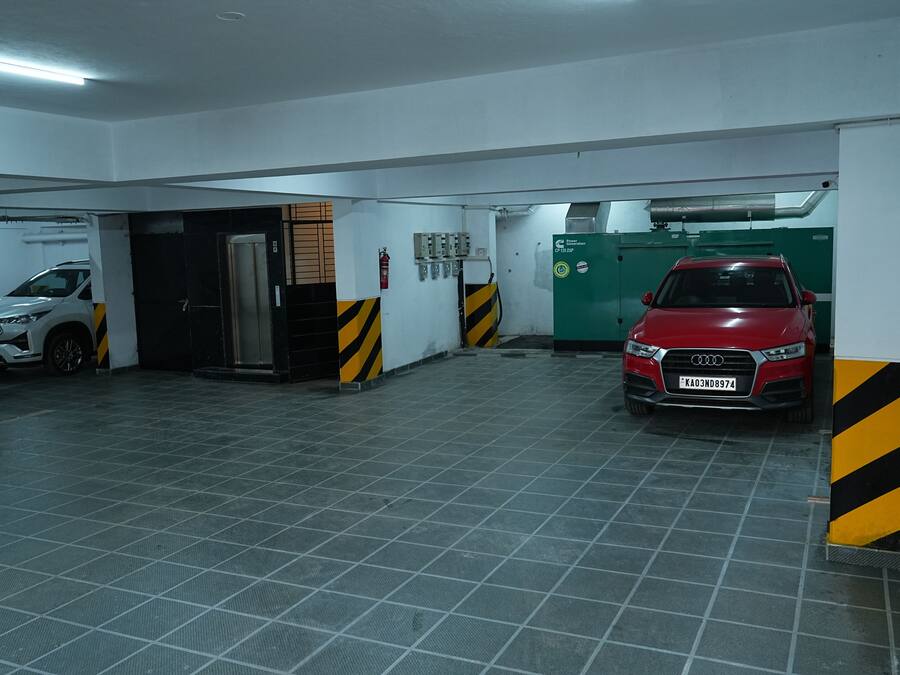 A parking garage with two cars, a white SUV and a red car, and a fire extinguisher on the wall.