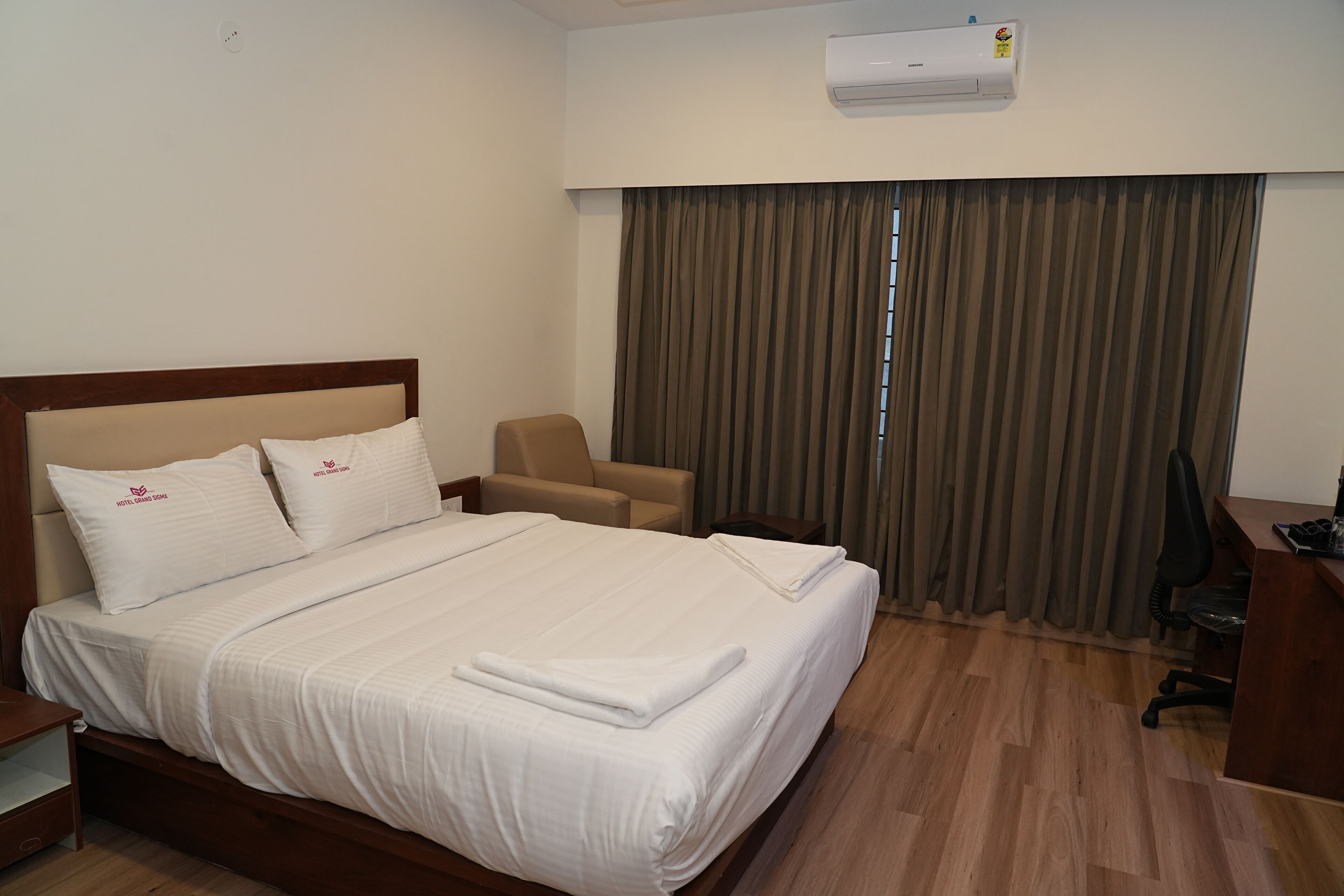 Een hotelkamer met een bed, een stoel, een bureau en een airconditioning.