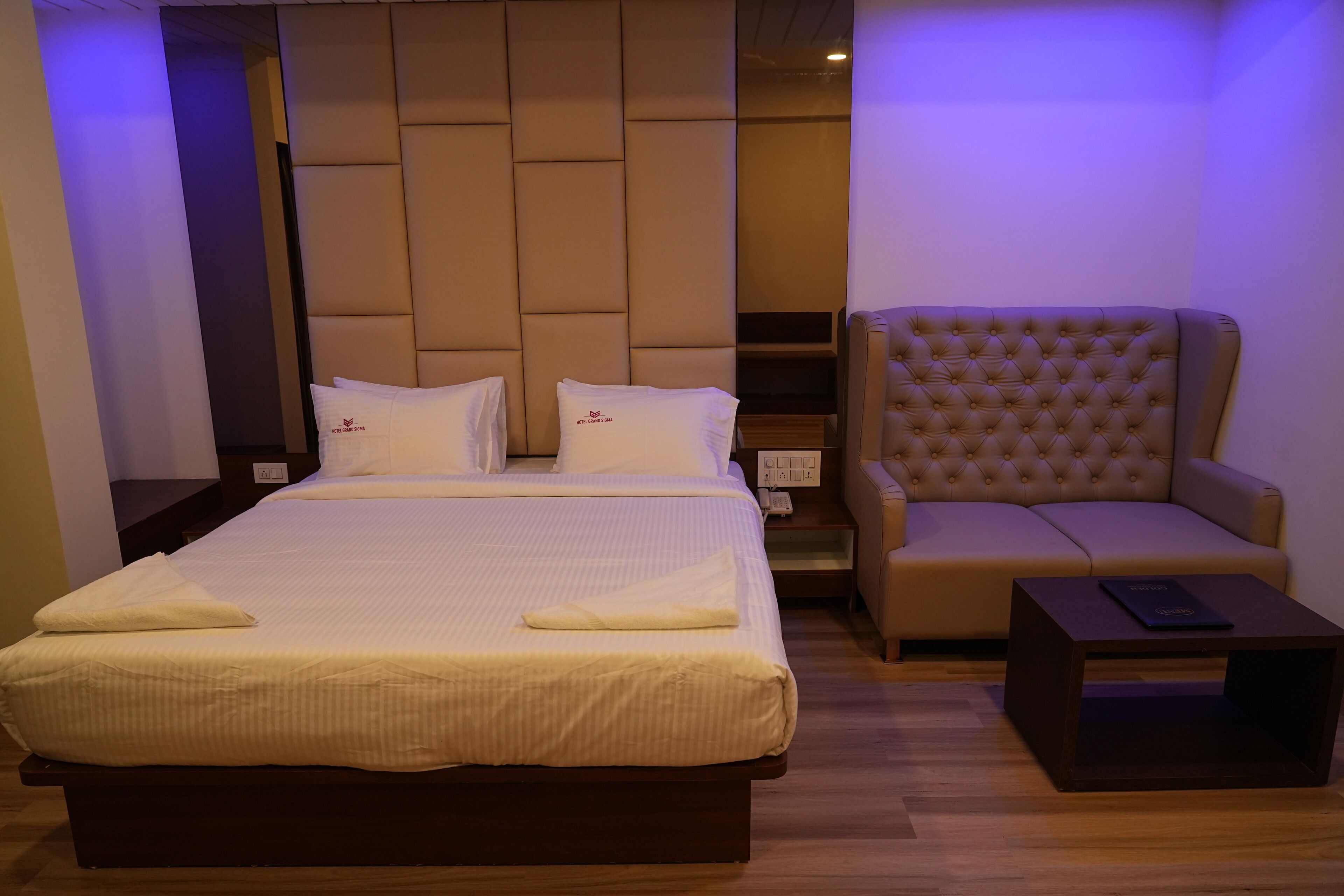 A hotel room with a large bed, a sofa, and a small table.