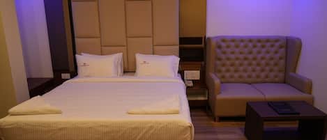 A hotel room with a large bed, a sofa, and a small table.