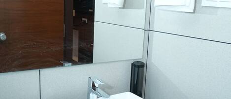 A bathroom with a white sink, a mirror, and a towel rack.