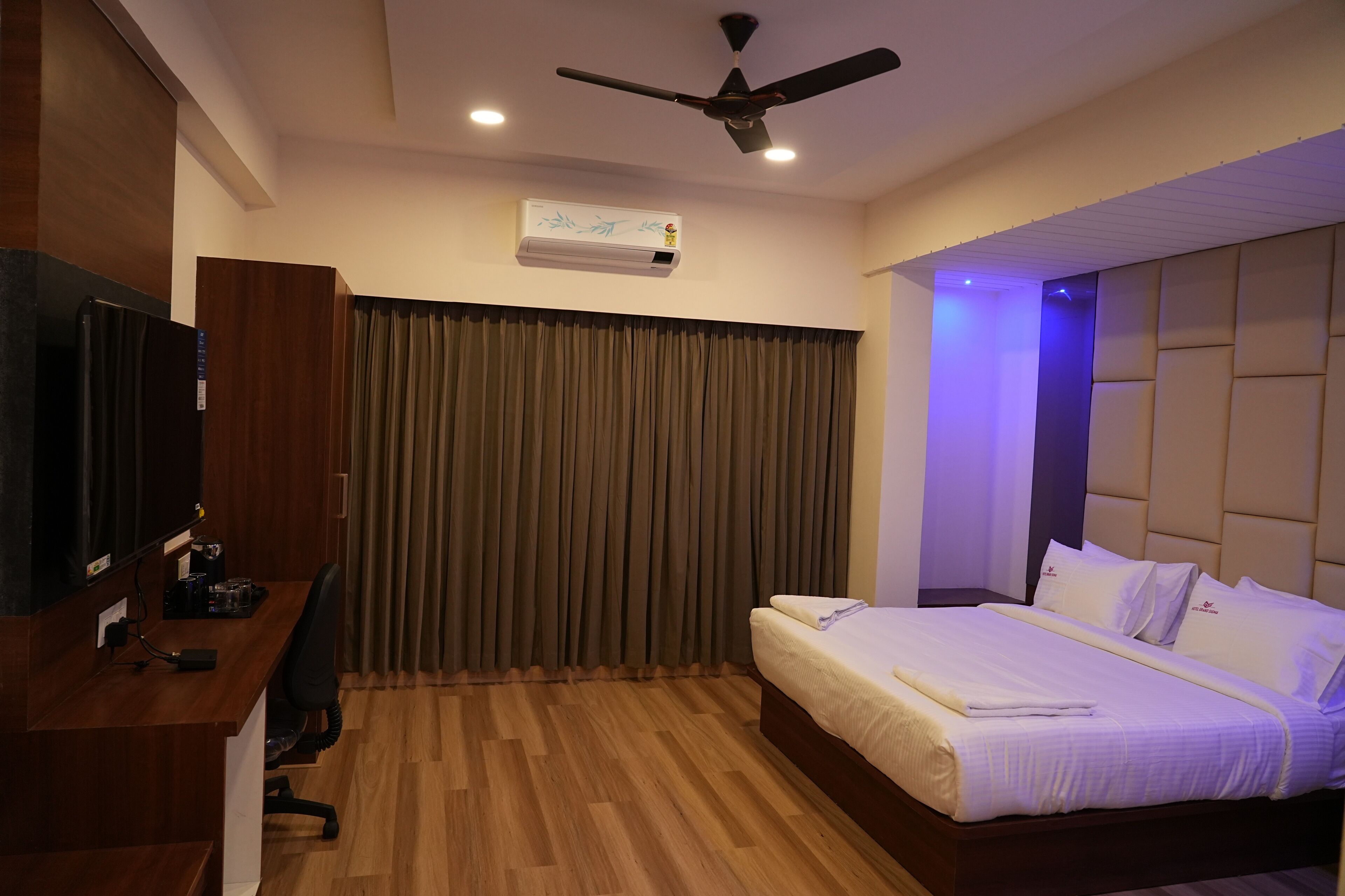 A hotel room with a bed, desk, and ceiling fan.