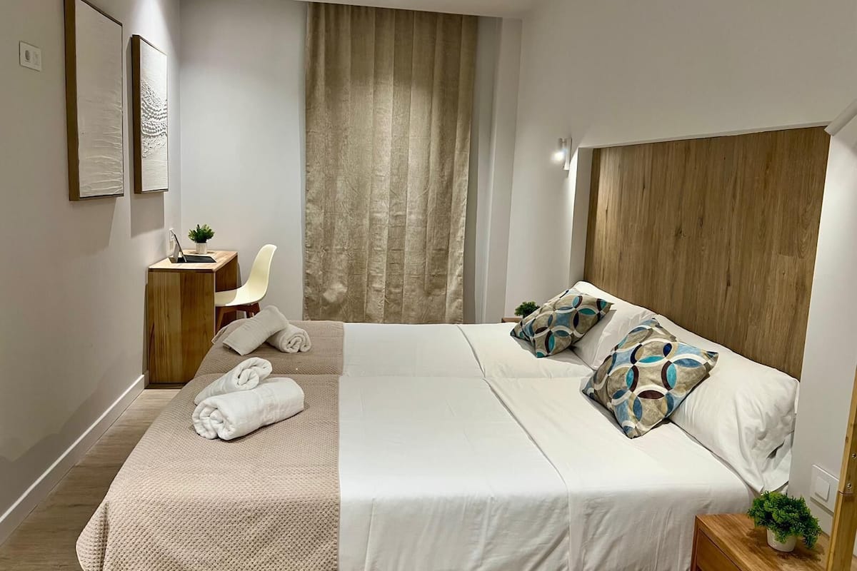 A modern hotel room with a large bed, a desk, and a chair.