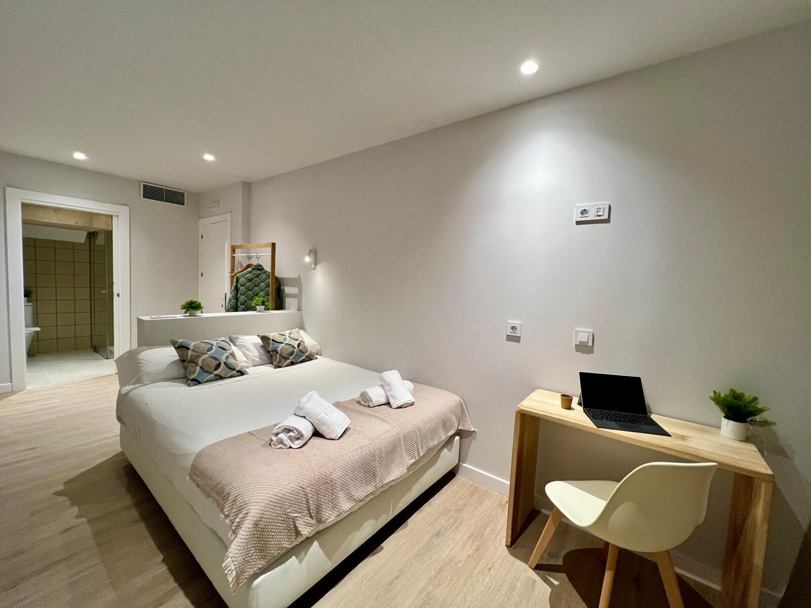 Une chambre moderne avec un lit, une table de chevet et un bureau avec un ordinateur portable.