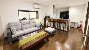 Una sala de estar moderna con un sofá, una mesa de centro y una zona de cocina con un taburete de bar.
