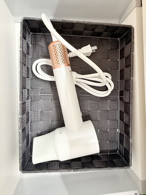 A white portable air purifier with a filter and power cord inside a black woven basket.