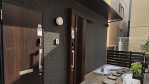 Una entrada moderna con puerta de madera, teclado de combinación y un pequeño espacio exterior con escalones y jardín.